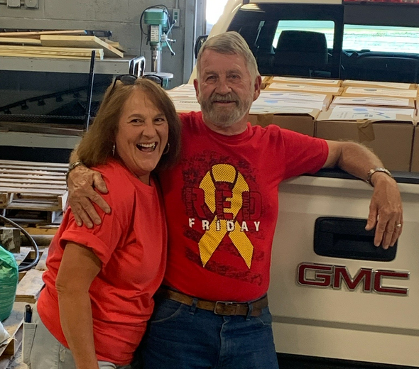A man and a woman are posing for a picture in front of a gmc truck.