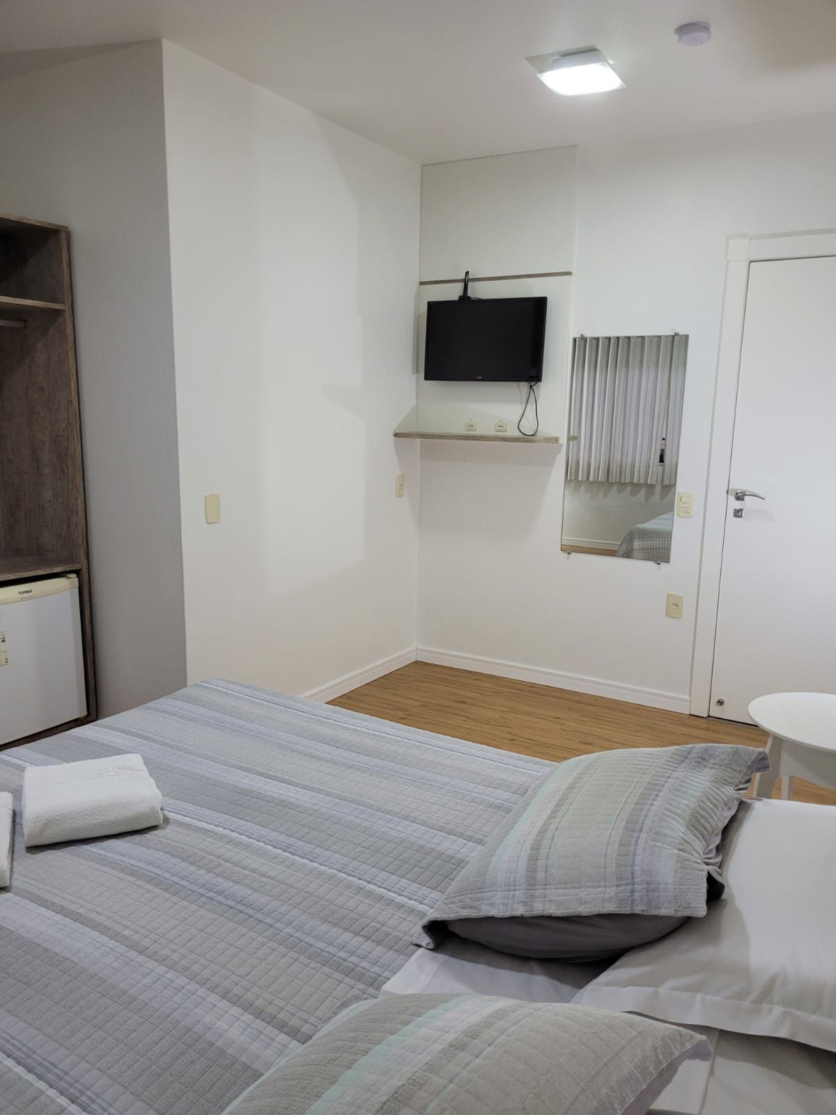 Um quarto de hotel com duas camas, uma televisão e um espelho.