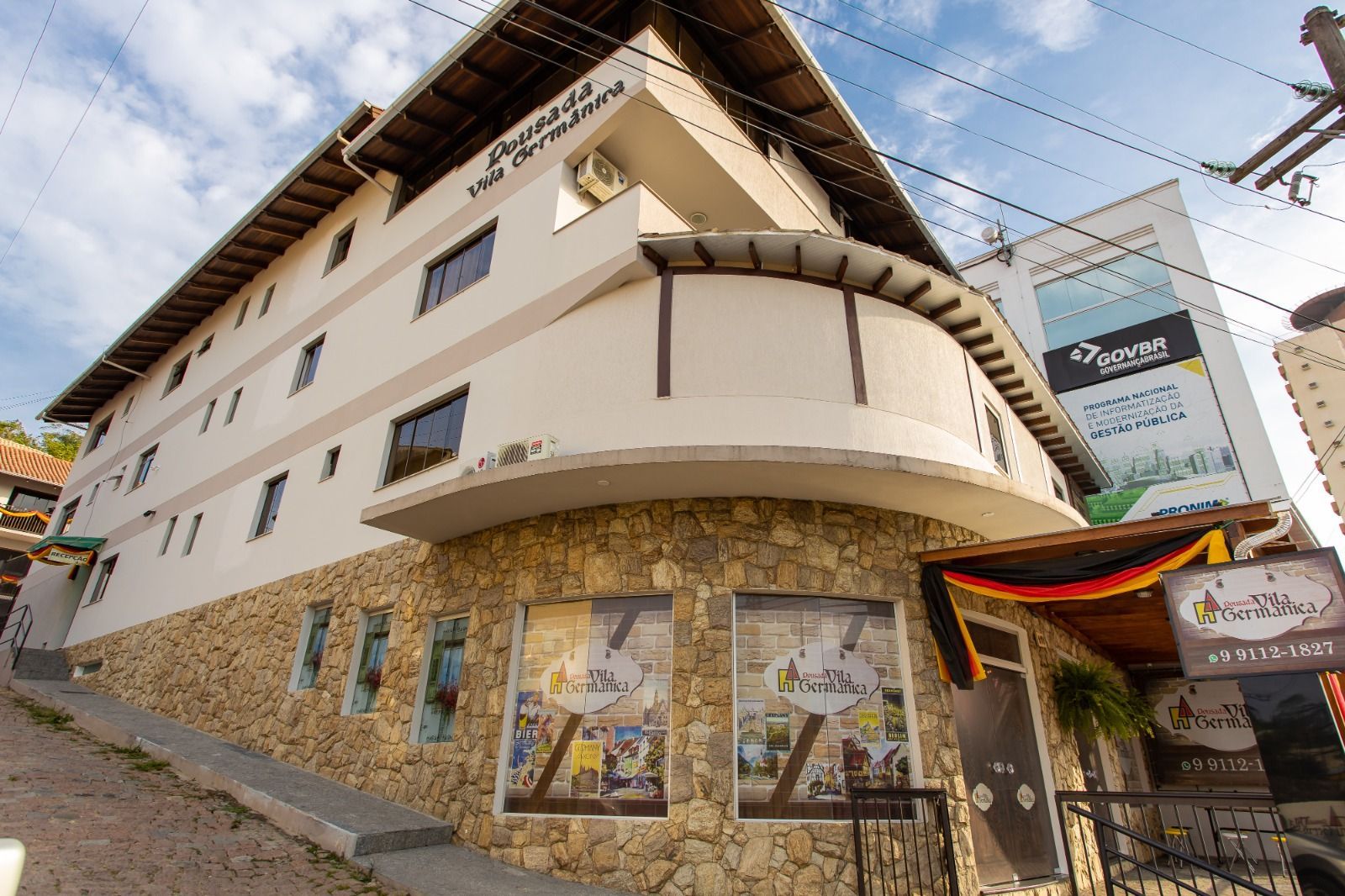 Um grande edifício branco com muitas janelas está situado no topo de uma colina.