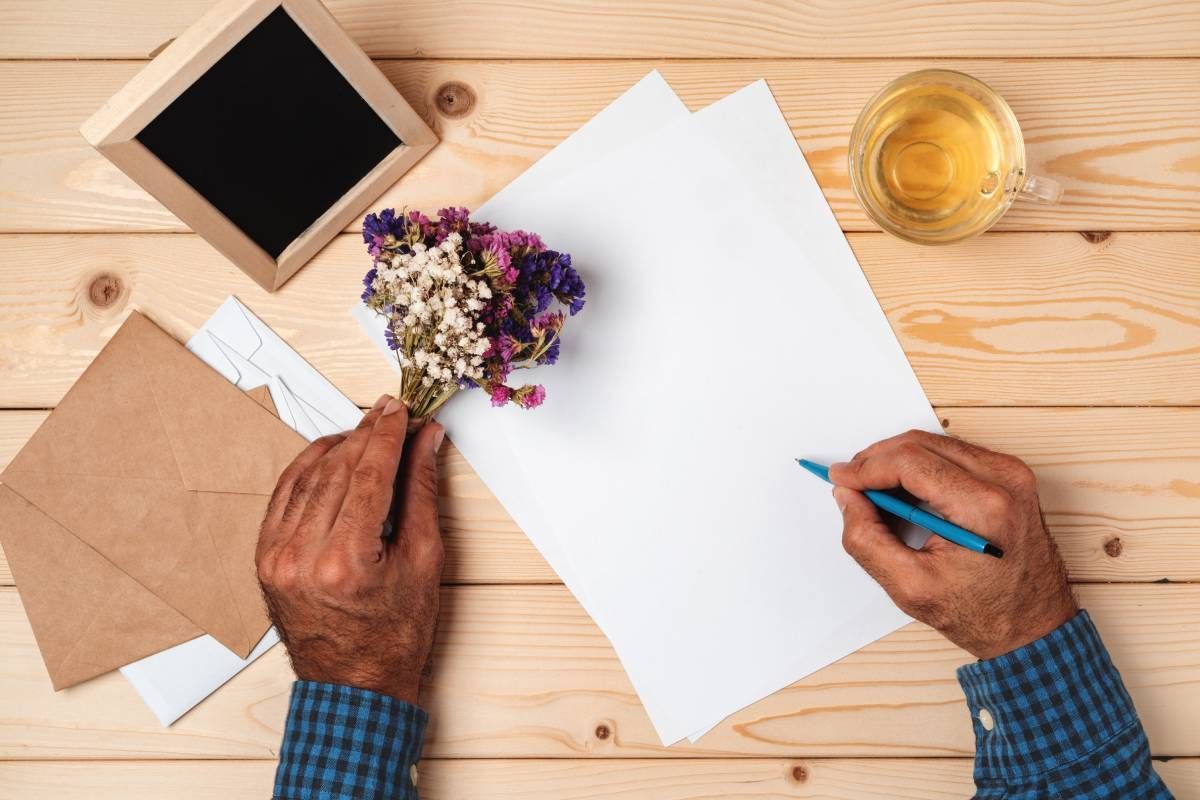 Hands writing an obituary on paper