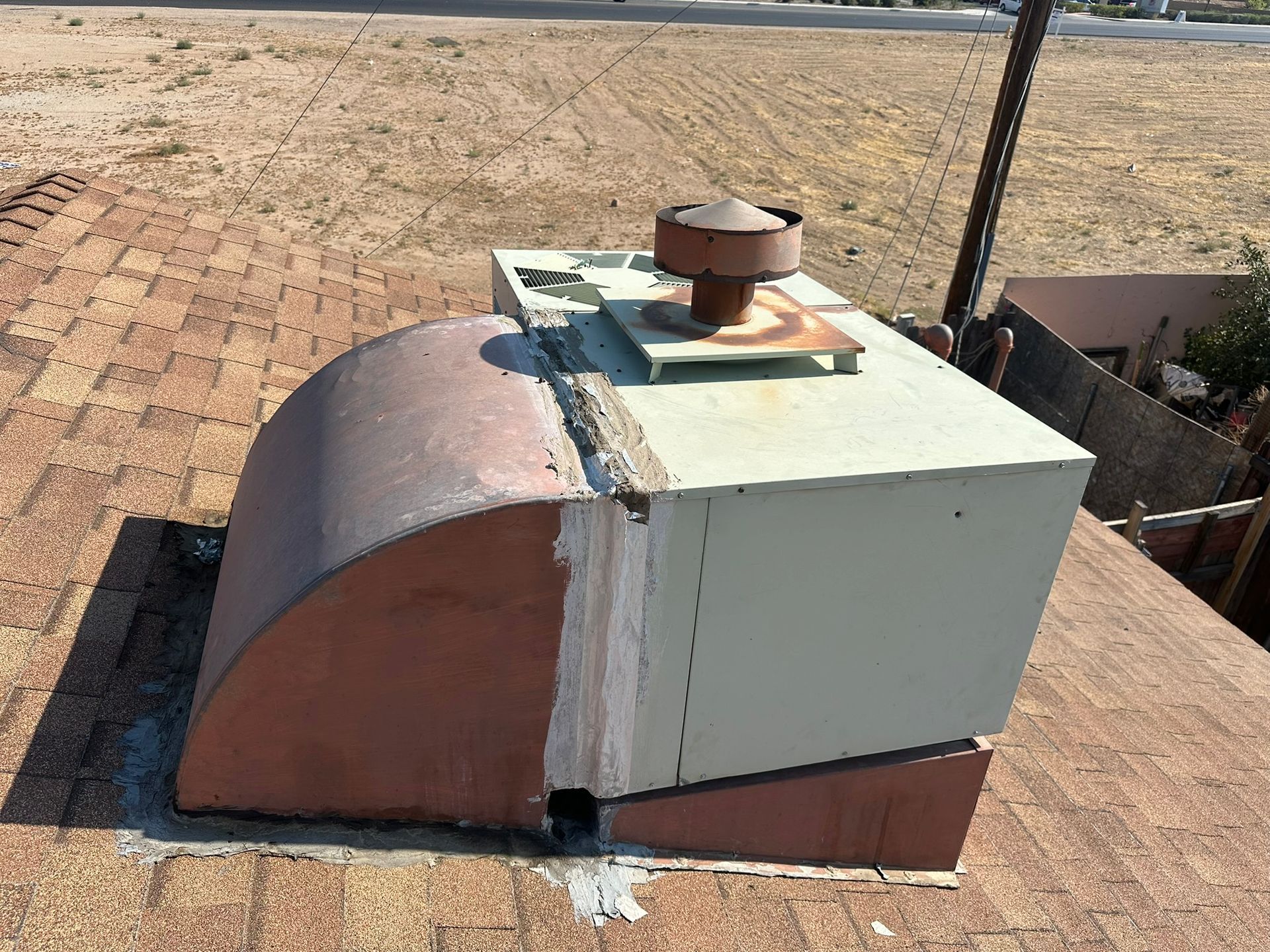 A rusty metal chimney with a vent cap sits on a brown rooftop.