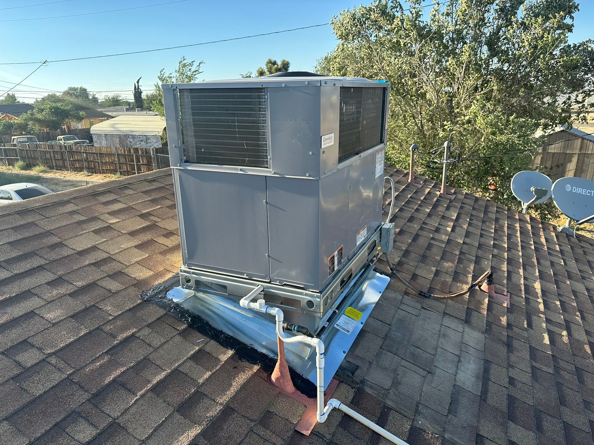 Gray HVAC unit on a rooftop, with pipes connected.