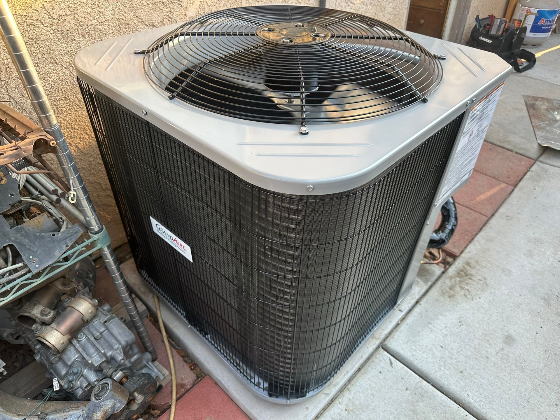 Air conditioning unit outside a building, with fan and metal grates.