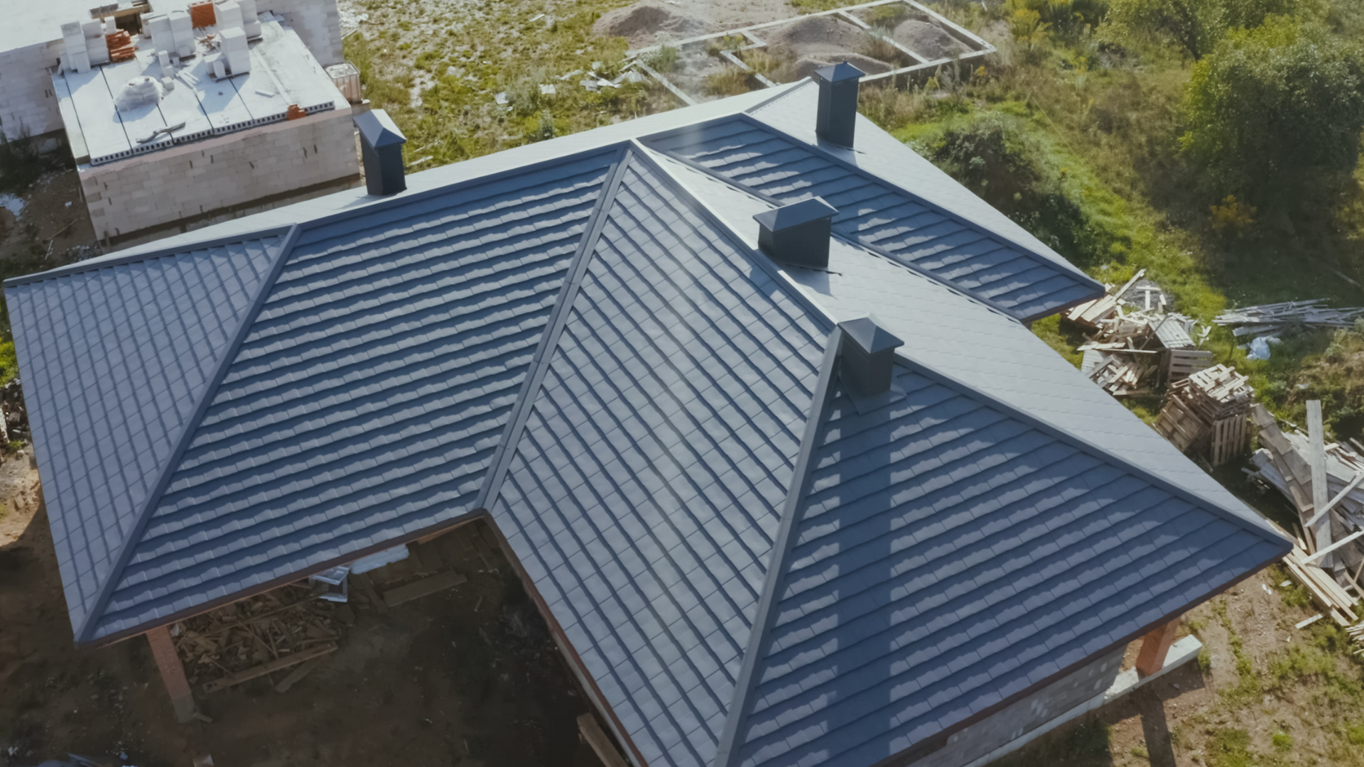Damaged asphalt shingle roof with exposed underlayment, showing a section needing repair. Gray shingles and white gutter.