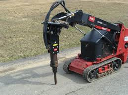 Red track loader with hydraulic hammer breaking concrete.