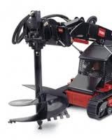 Black and red Toro mini skid steer with an auger attachment drilling a hole.