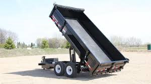 Black dump trailer with raised bed, in a sunny outdoor setting.