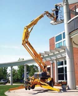 Yellow boom lift with a person in the basket working on a building.