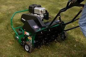 Green lawn aerator in use on grass.