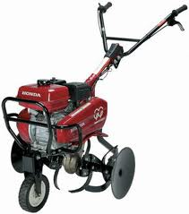 Red Honda tiller with black handles and wheels, used for gardening.