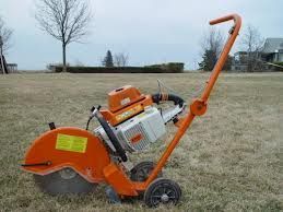 Orange concrete saw on wheels in a grassy field.