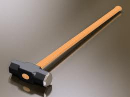 Sledgehammer on a reflective surface; black head, wooden handle, tan and brown color.
