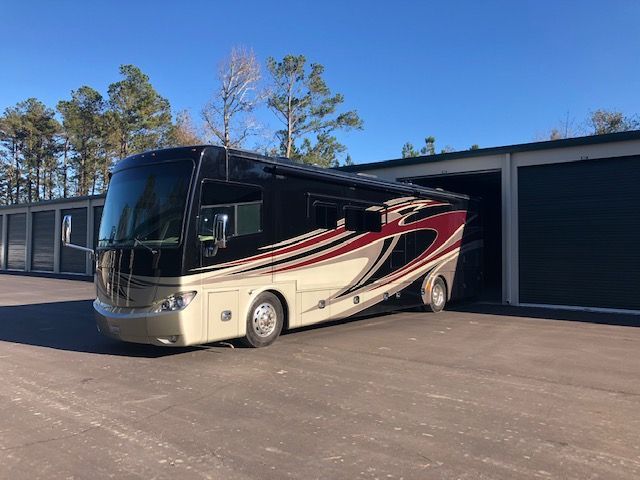 RV parked outside a row of storage units; tan, black and burgundy color scheme.