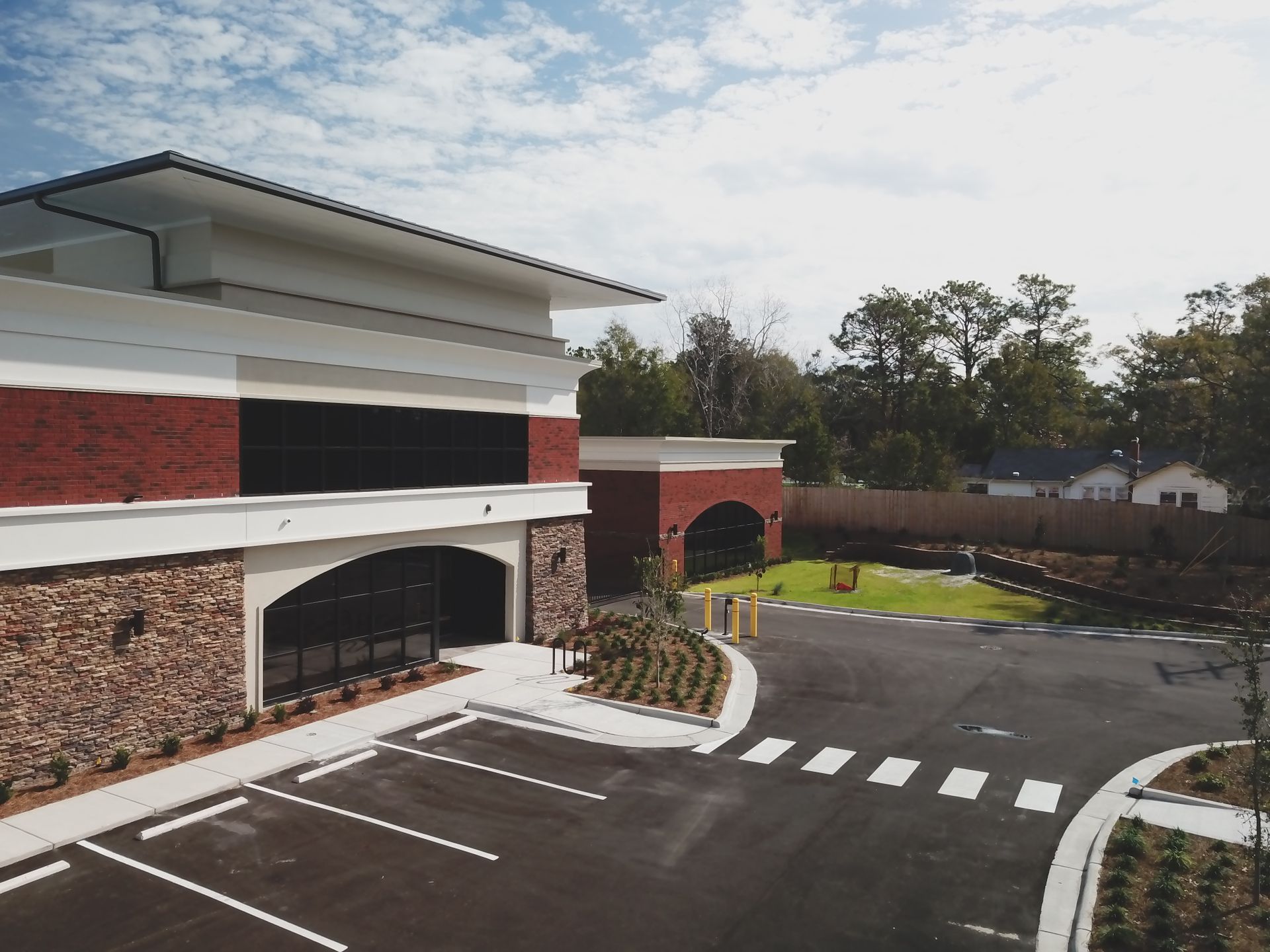 Exterior view of a modern brick and stone building with a parking lot and a landscaped area.