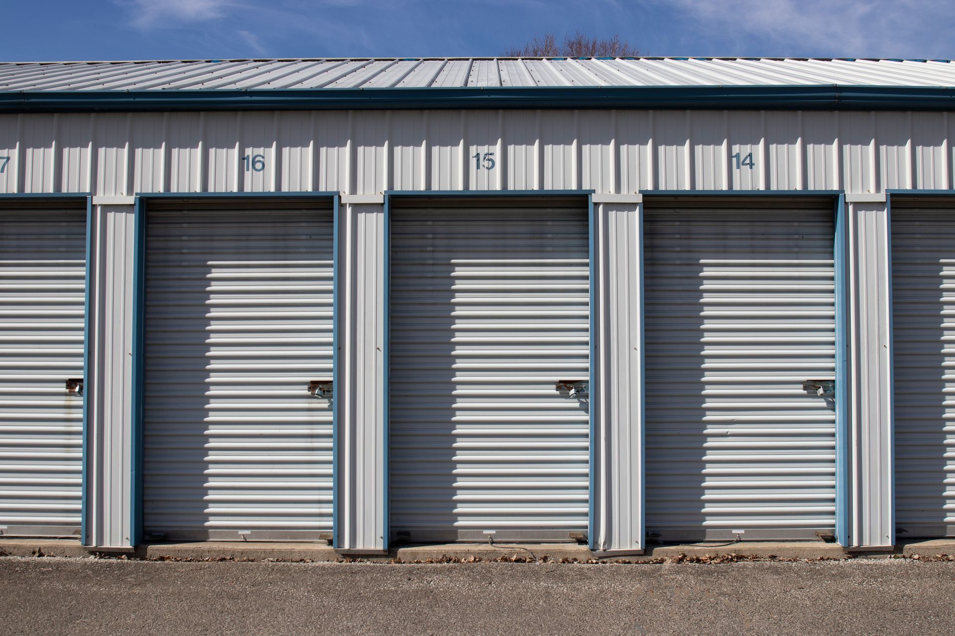 Clean self-storage facility hallway with multiple metal roll-up doors and a cart loaded with boxes.