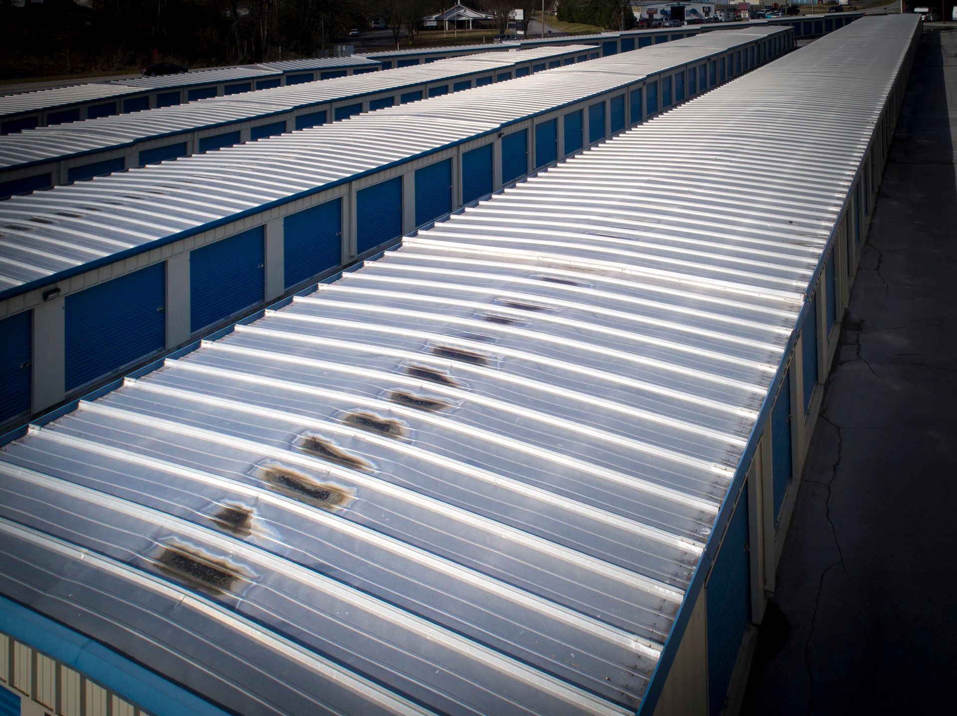 Rows of blue and white self-storage units with metal roofs in an outdoor storage facility.