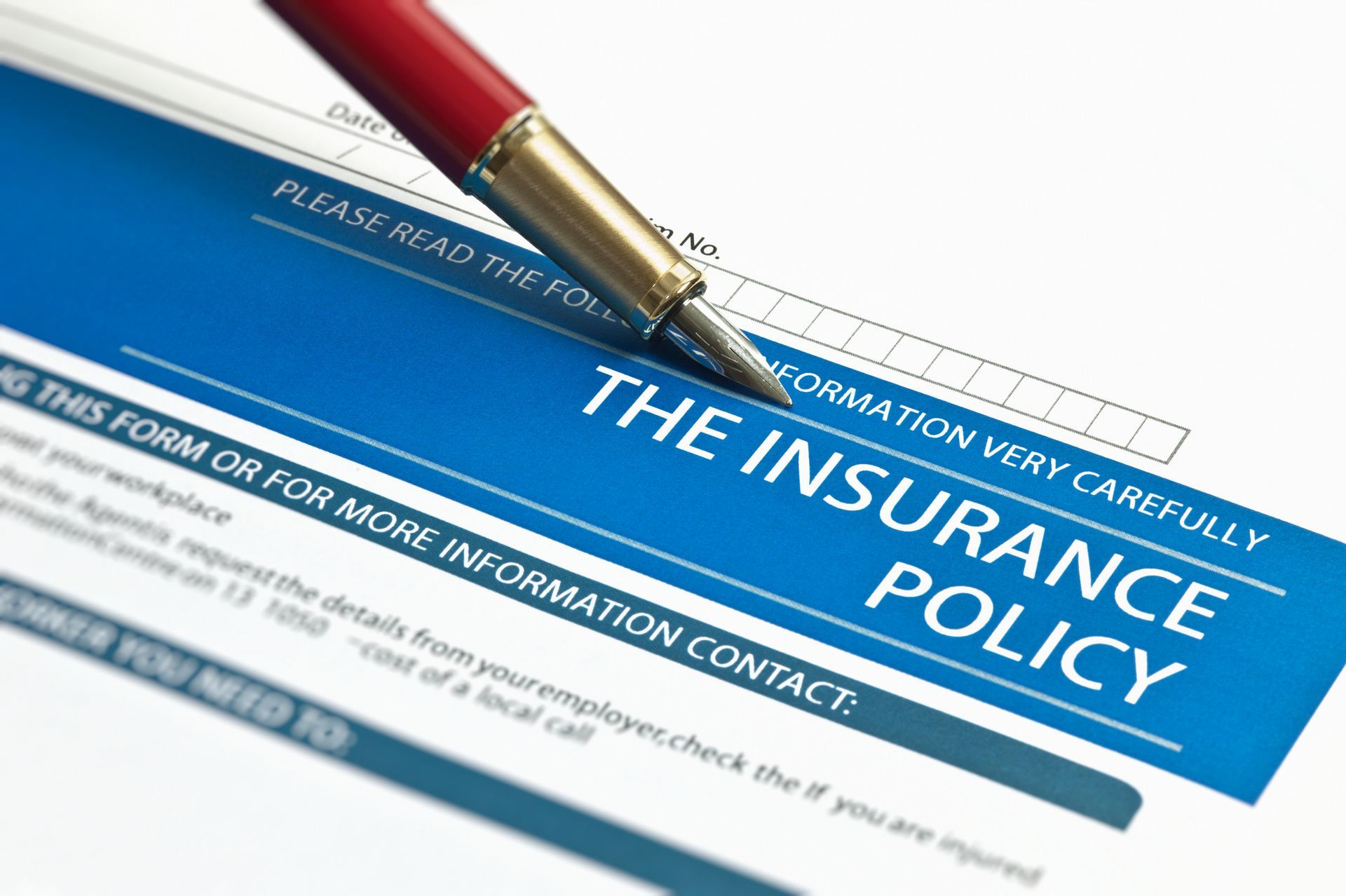 Close-up of an insurance policy form with a red pen resting on it. Blue and white text.