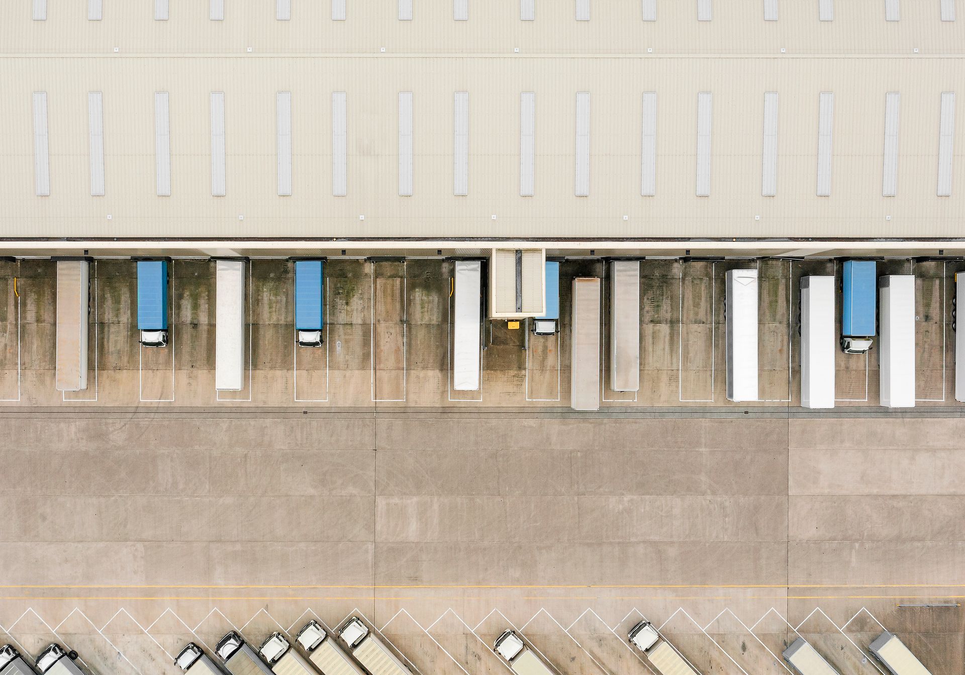 Overhead drone view of a vehicle storage facility with trucks.