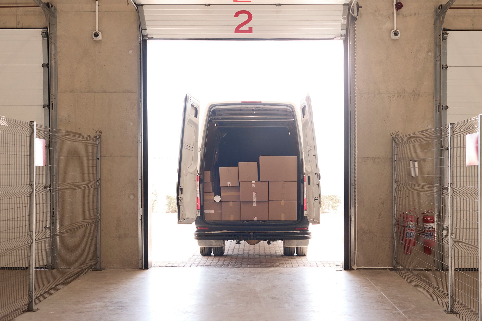 Delivery van with cardboard boxes parking into a storage facility dock.