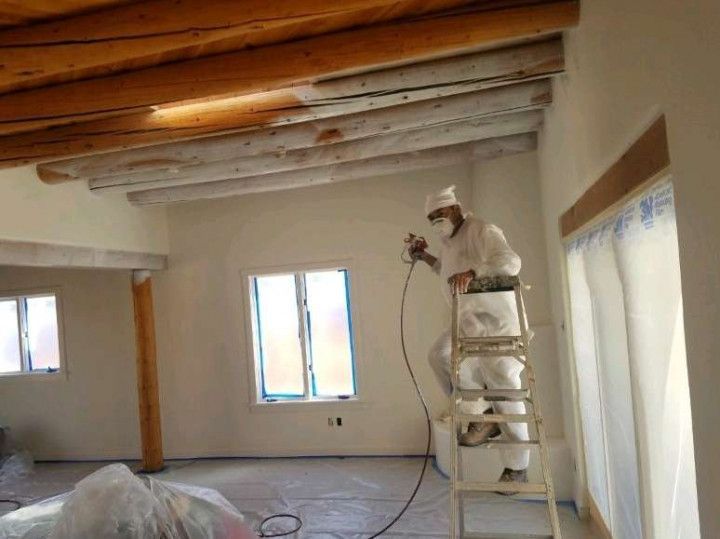 A man is standing on a ladder painting a room.