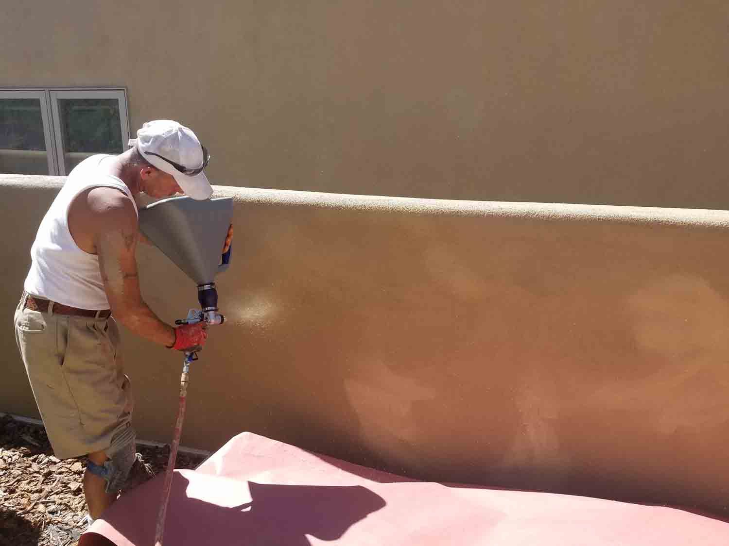 A man is painting a wall with a sprayer