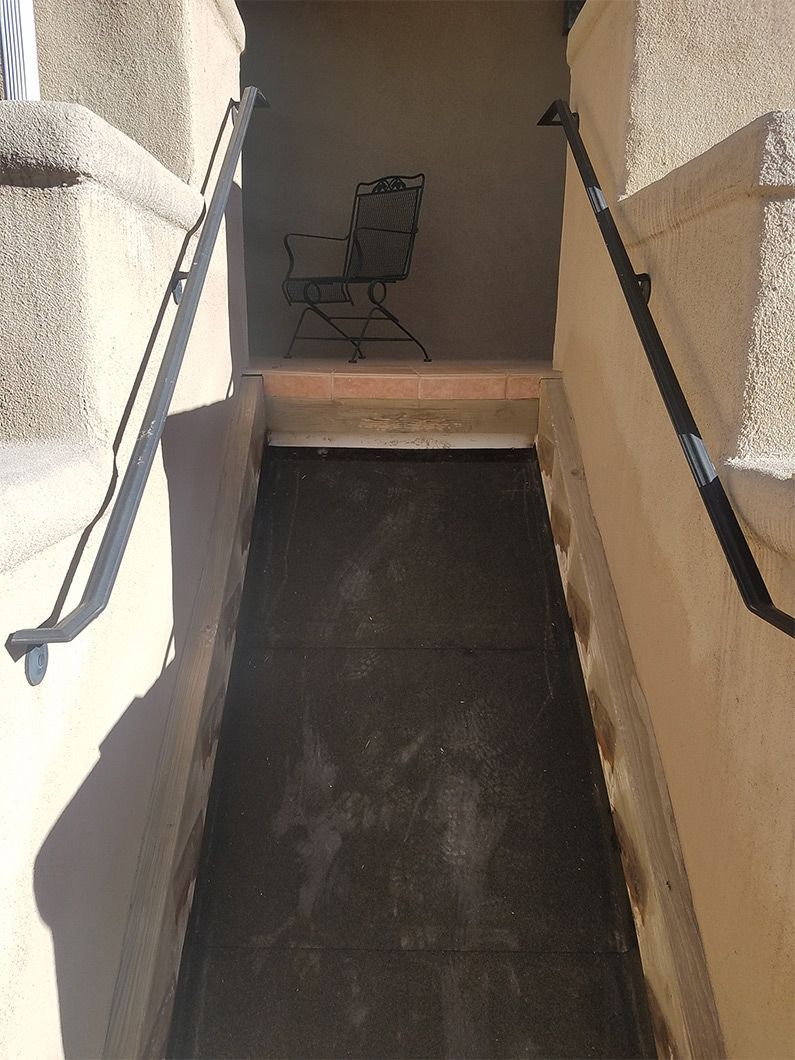 A narrow hallway with stairs and a chair in the background.