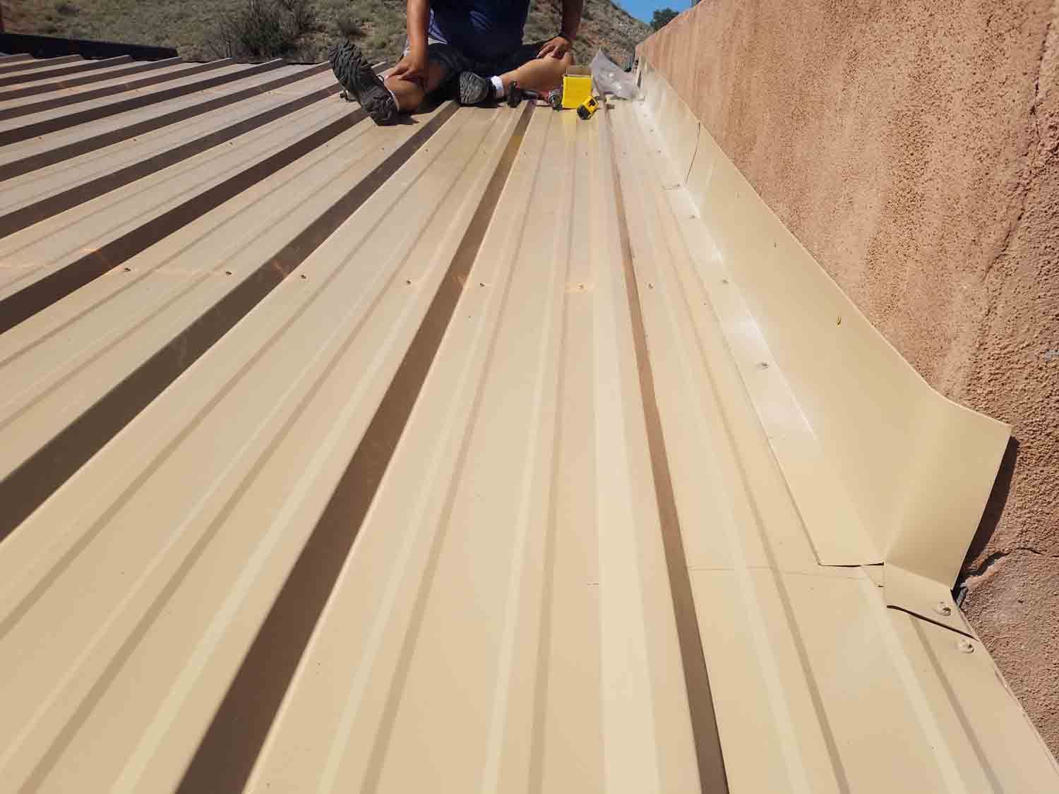 A man is sitting on top of a metal roof.