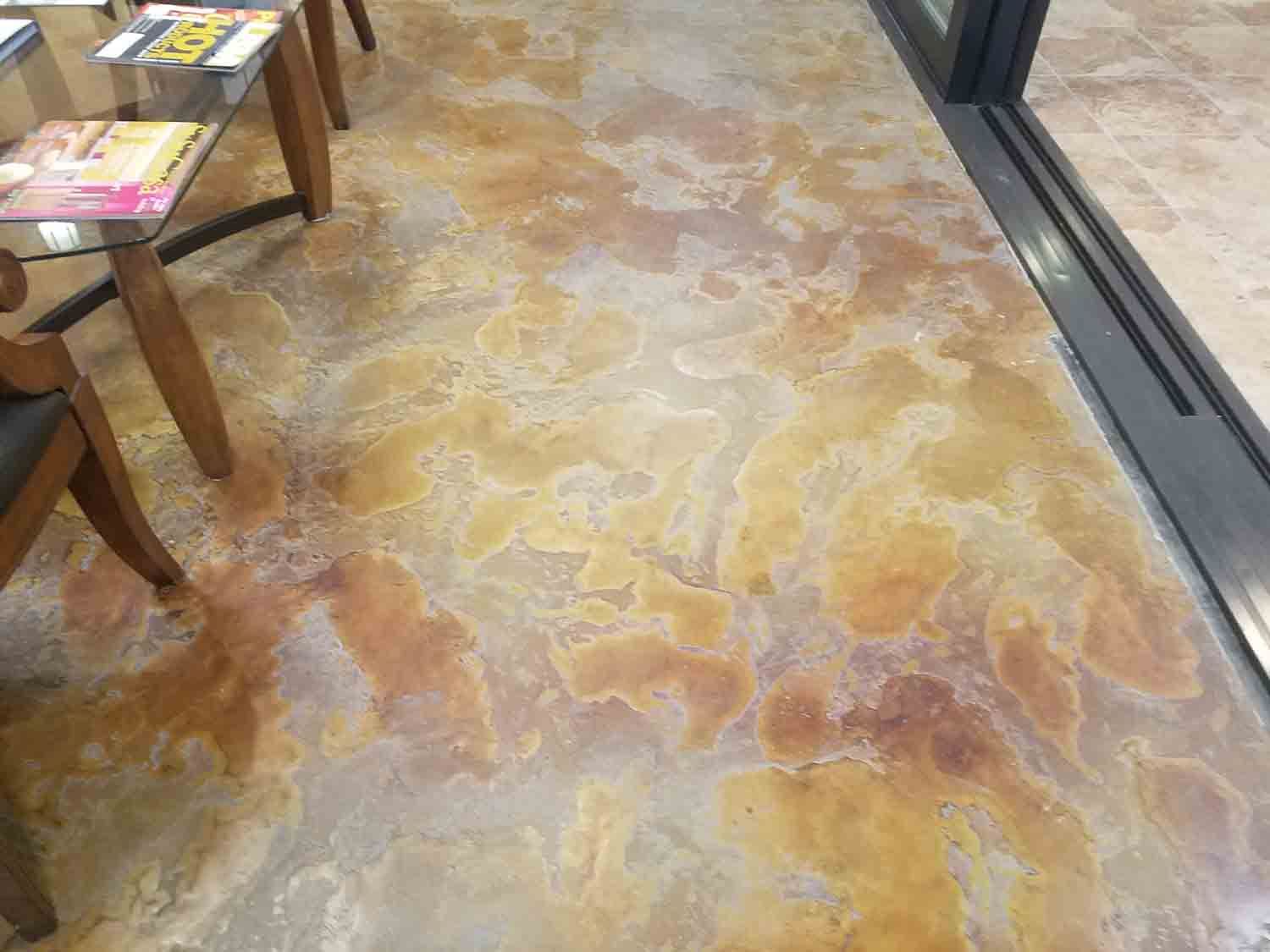 A marble floor in a waiting room with tables and chairs.