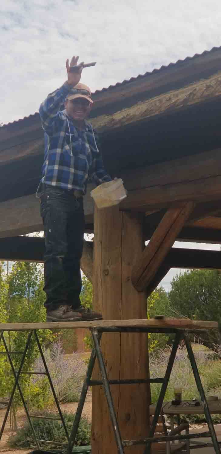 A man is standing on top of a wooden post.