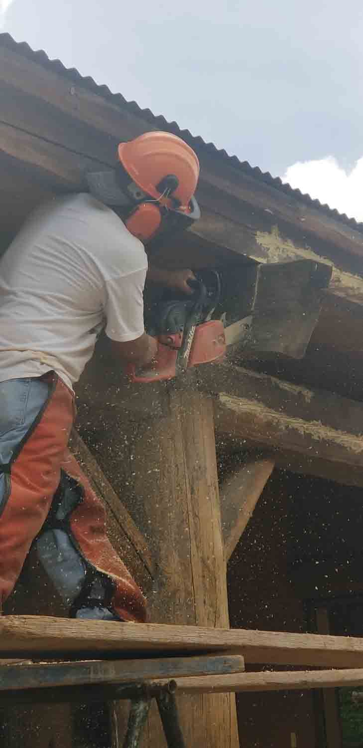 A man is cutting a tree trunk with a chainsaw.
