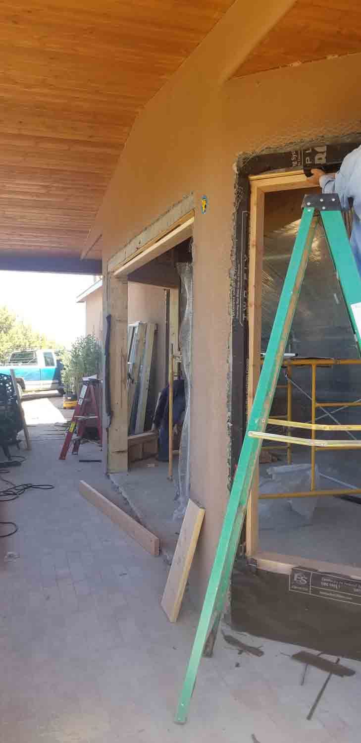 A man is standing on a ladder in front of a building under construction.