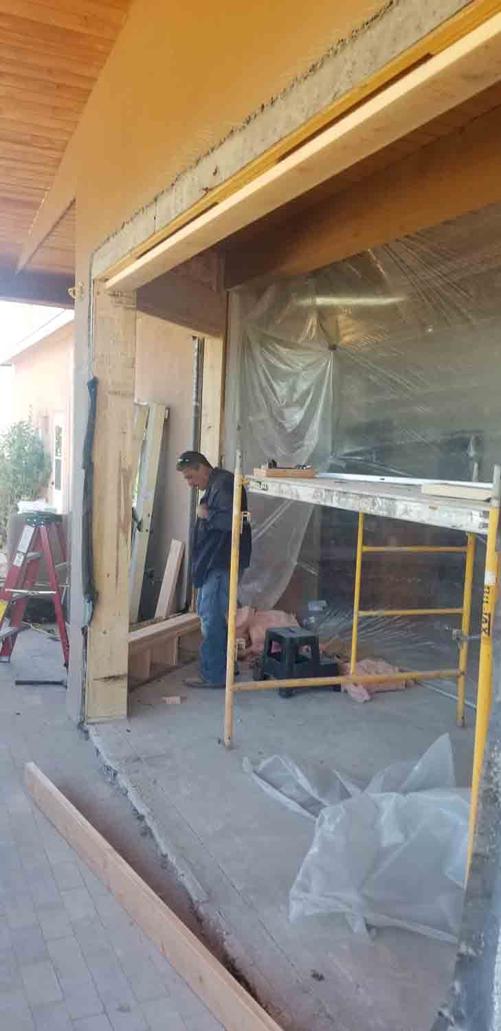 A man is standing on a scaffolding in front of a garage door.