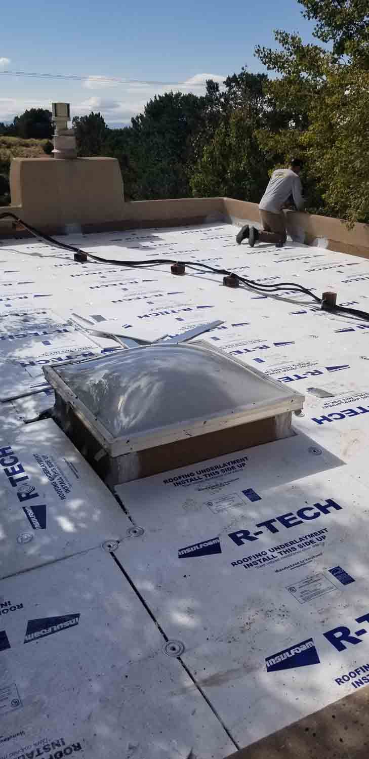 A man is working on a roof with a skylight.