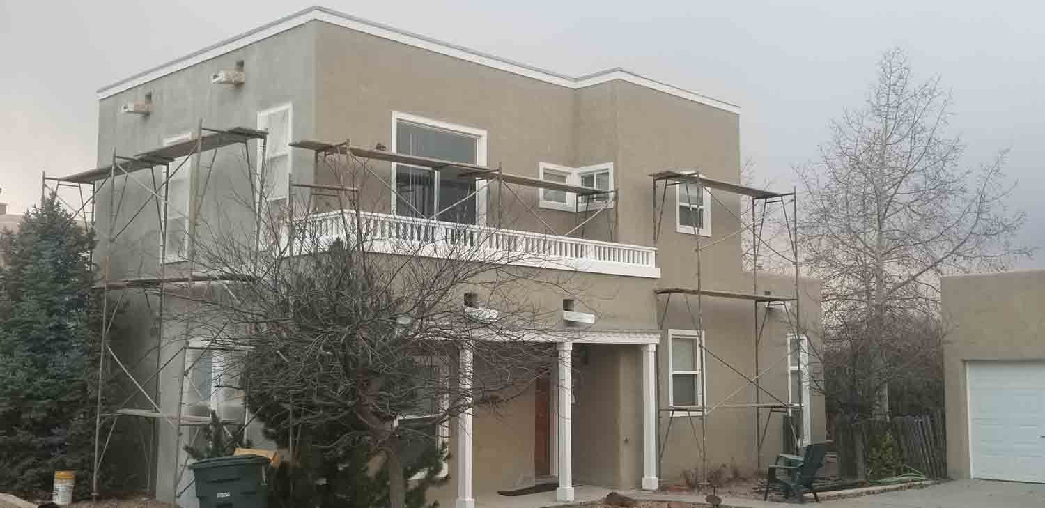 A large house with scaffolding around it is being painted.
