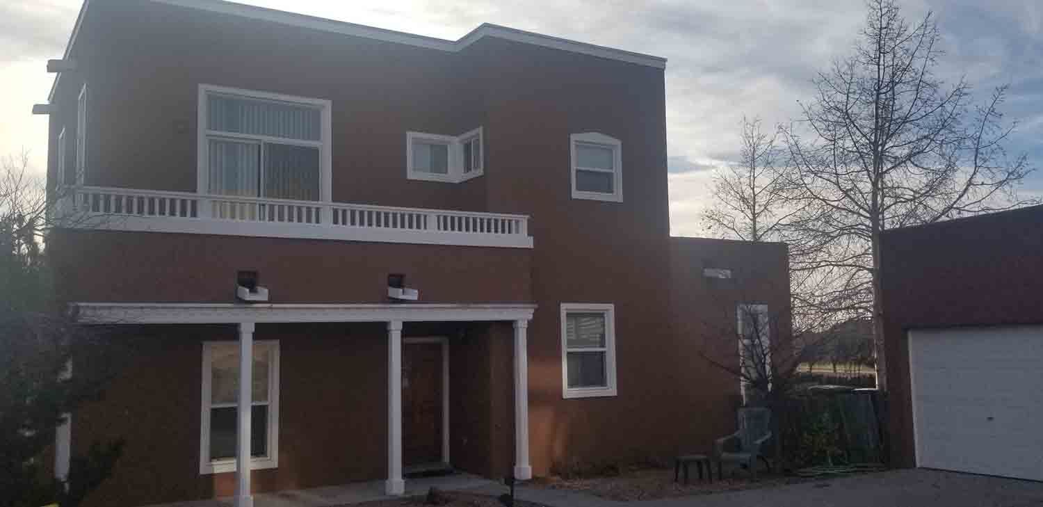 A large brown house with a white porch and a garage.