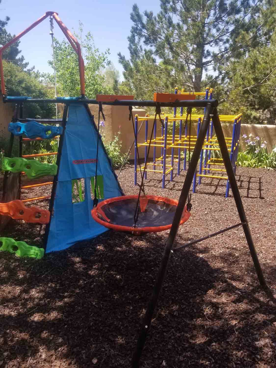 A playground with a swing set and a teepee