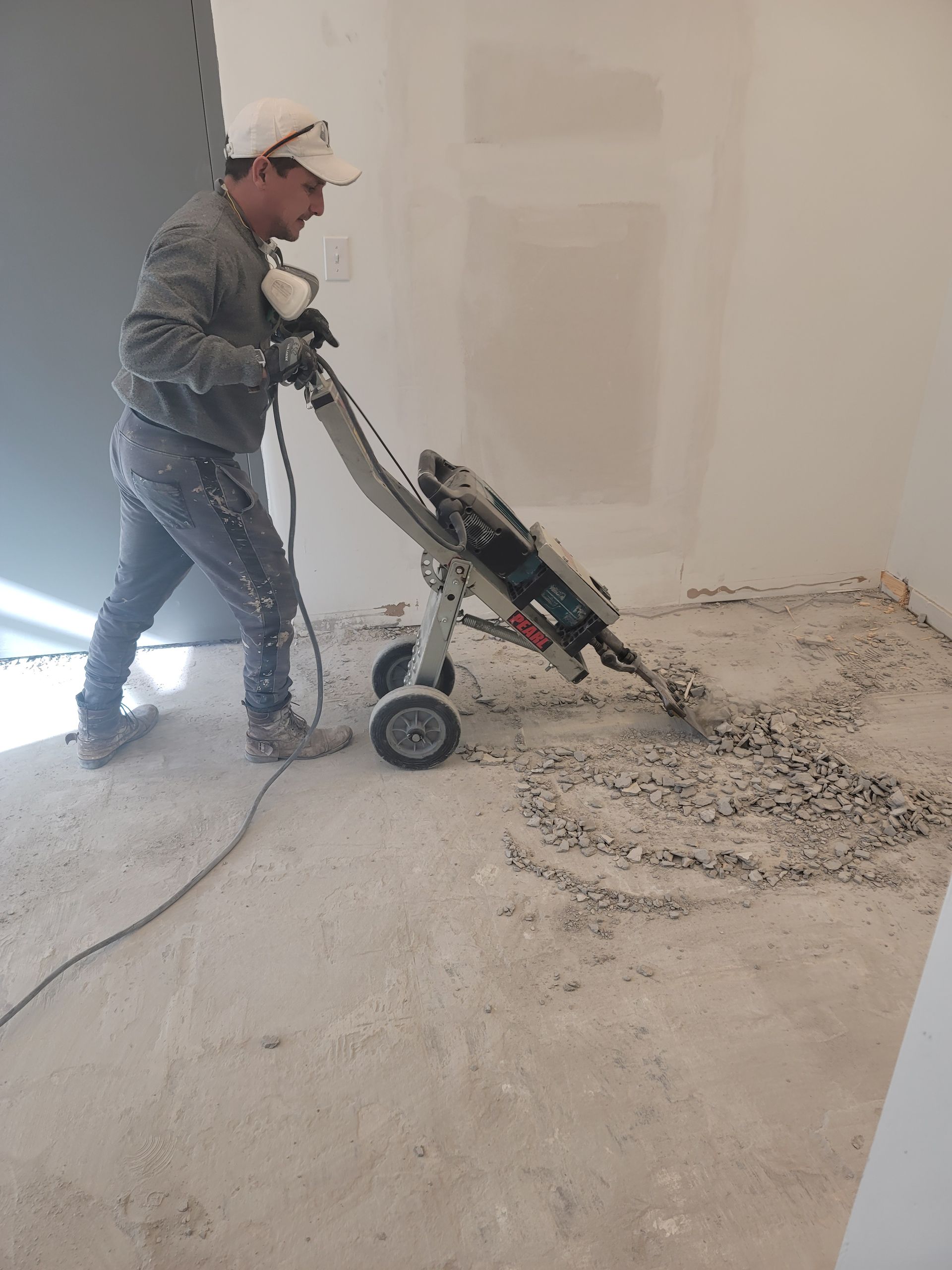 A man is using a machine to remove concrete from the floor.