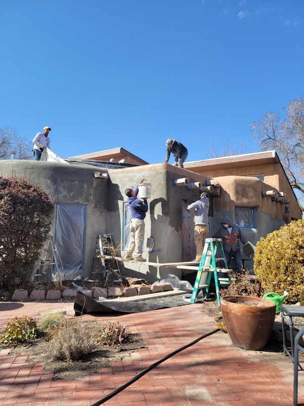 A group of people are working on the side of a house.