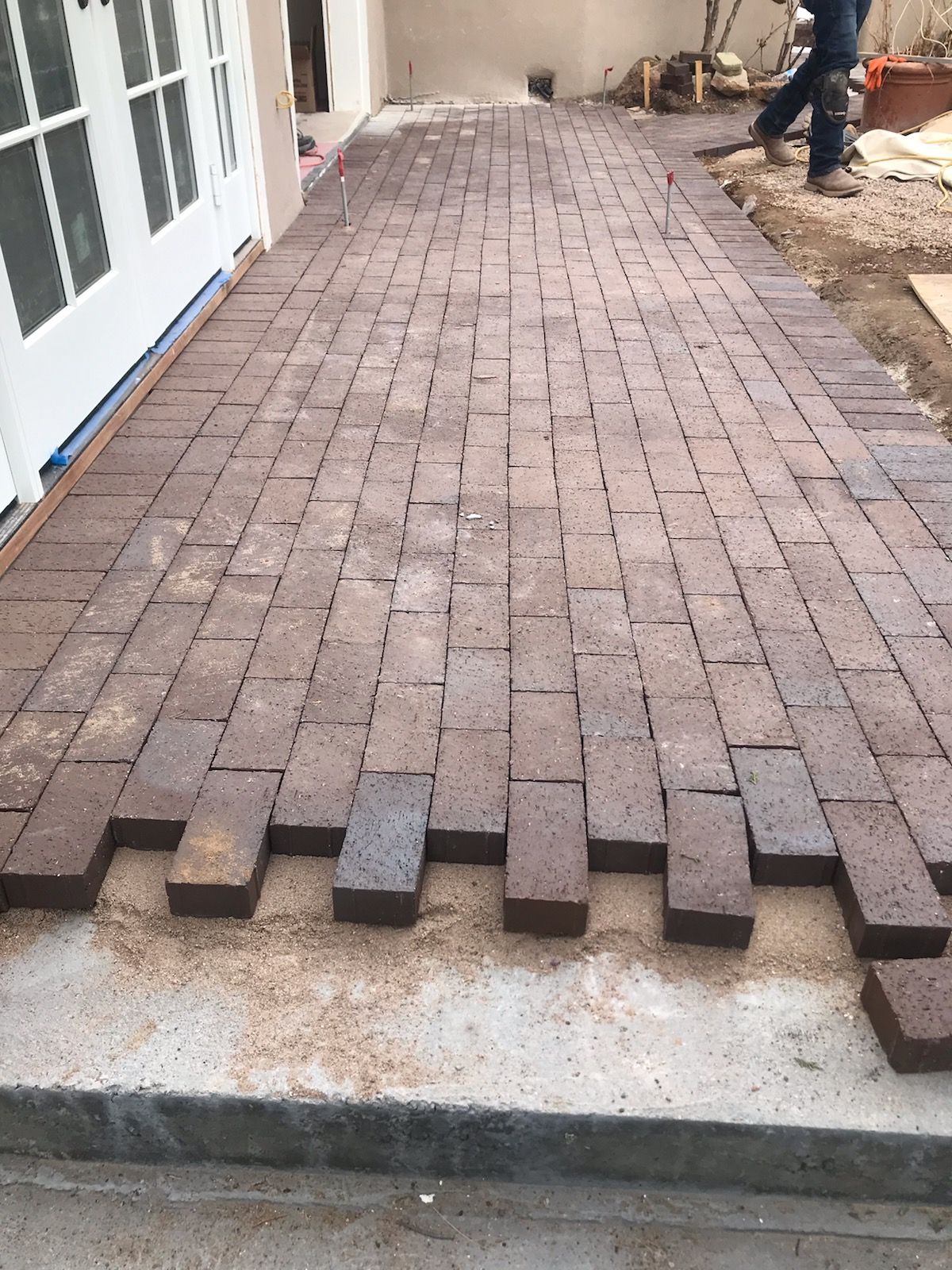 A brick walkway is being built in front of a house.