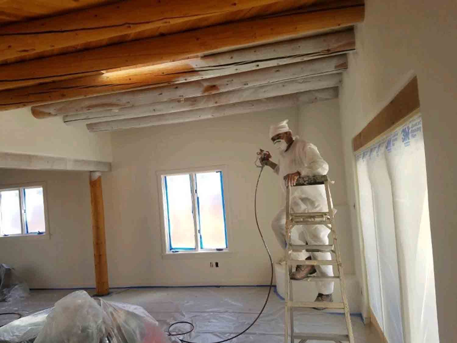 A man is standing on a ladder painting a room.