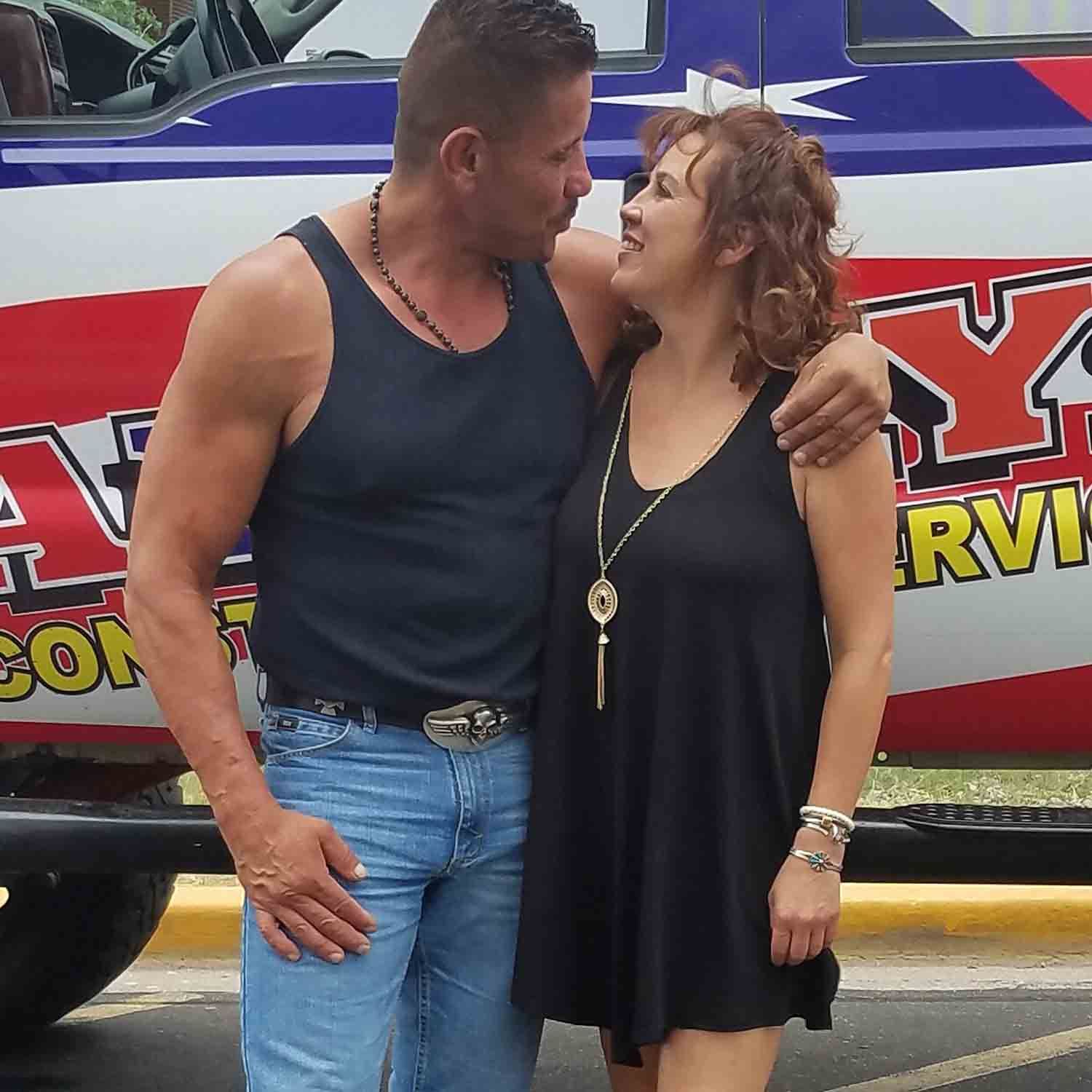 A man and woman are posing for a picture in front of a truck that says ny on it