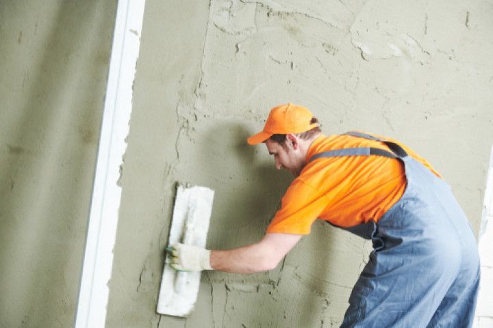 A man is plastering a wall with a trowel.