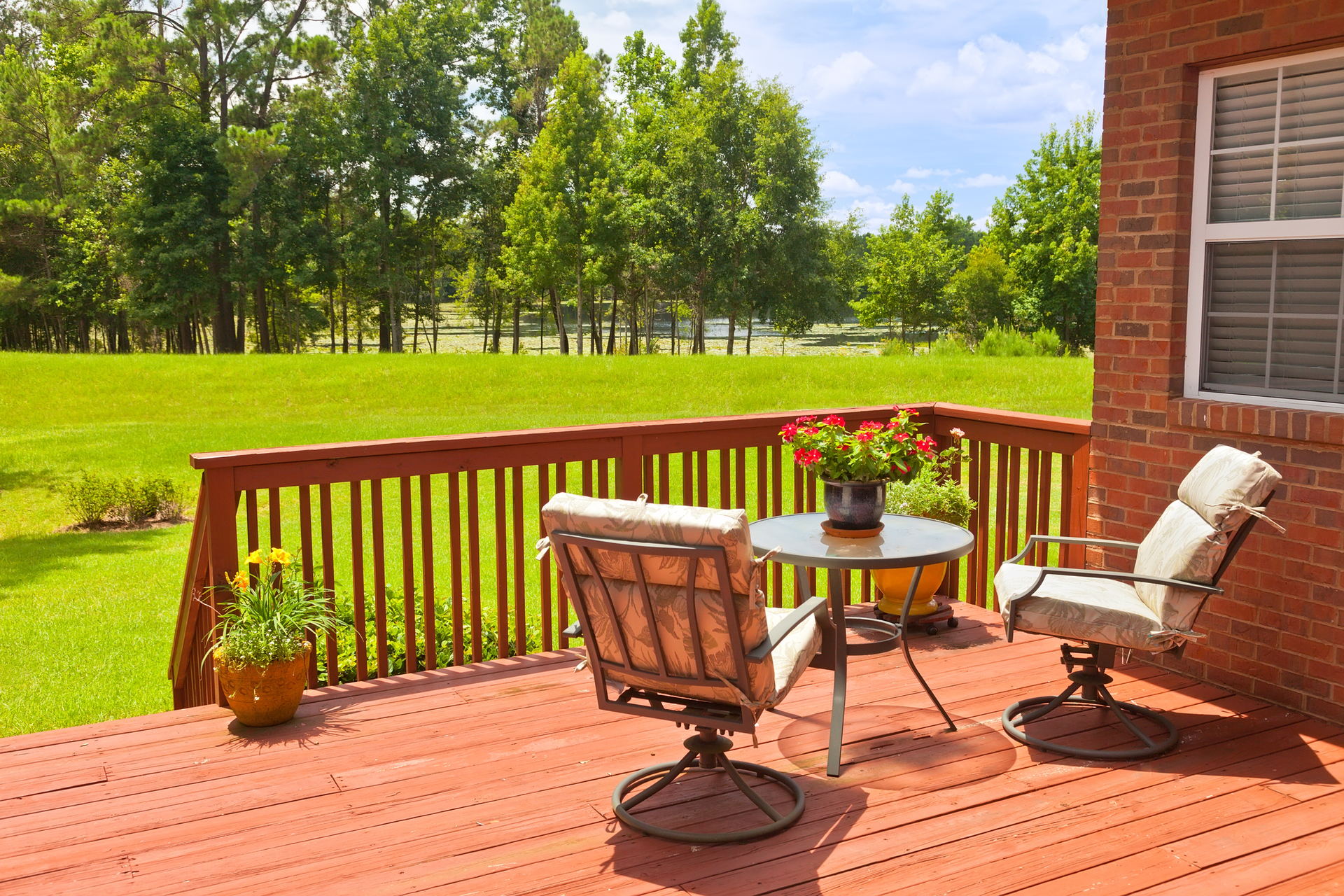 Residential backyard deck overlooking lawn and lake.