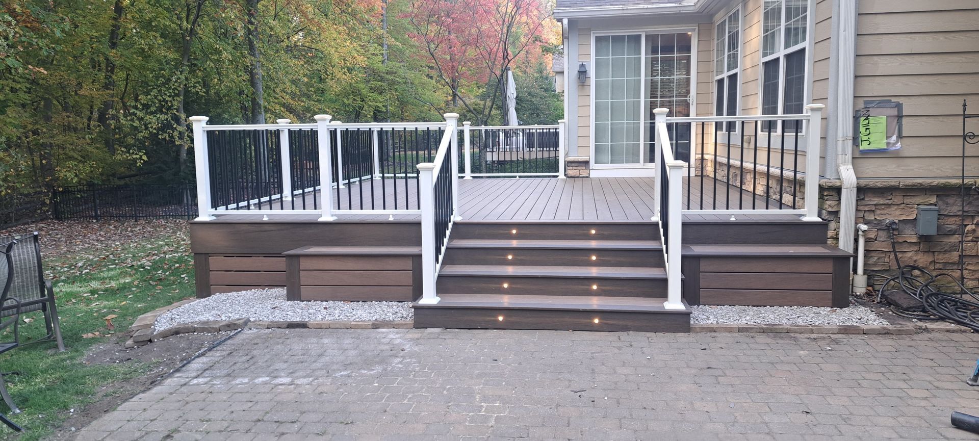 Deck with steps, railing, and lights. Brown deck and steps, white railing, in an outdoor setting.
