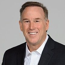 A man is sitting on a couch talking to two older people.