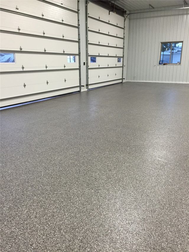 A garage with a gray floor and white garage doors.