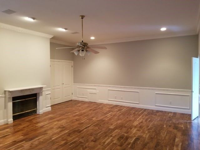 An empty living room with a fireplace and ceiling fan.
