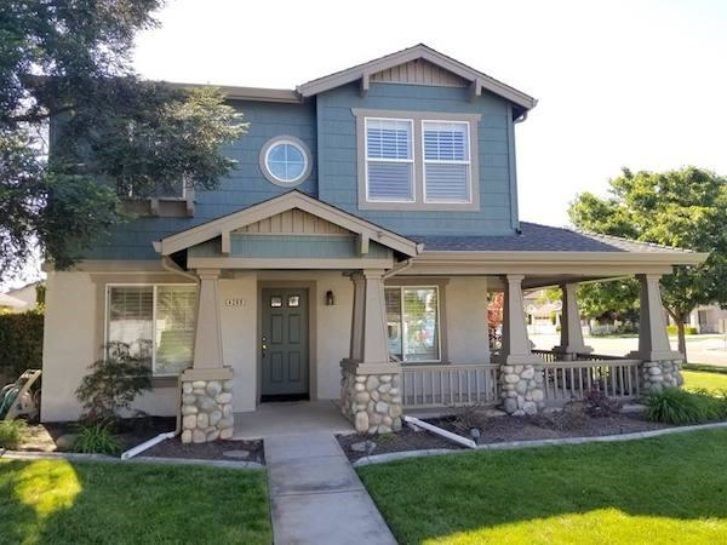 a blue and gray house with a porch and a large window .