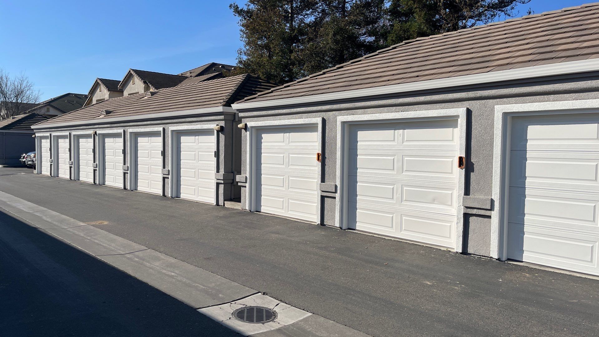 A row of white garage doors on the side of a building.