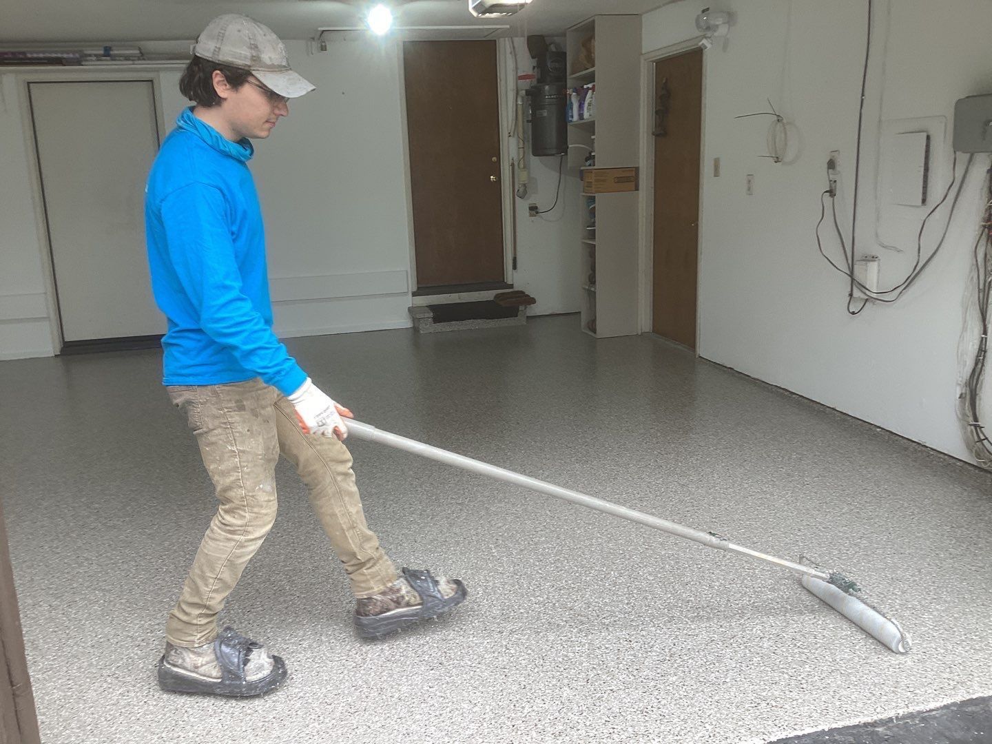 A man is cleaning a garage floor with a mop.